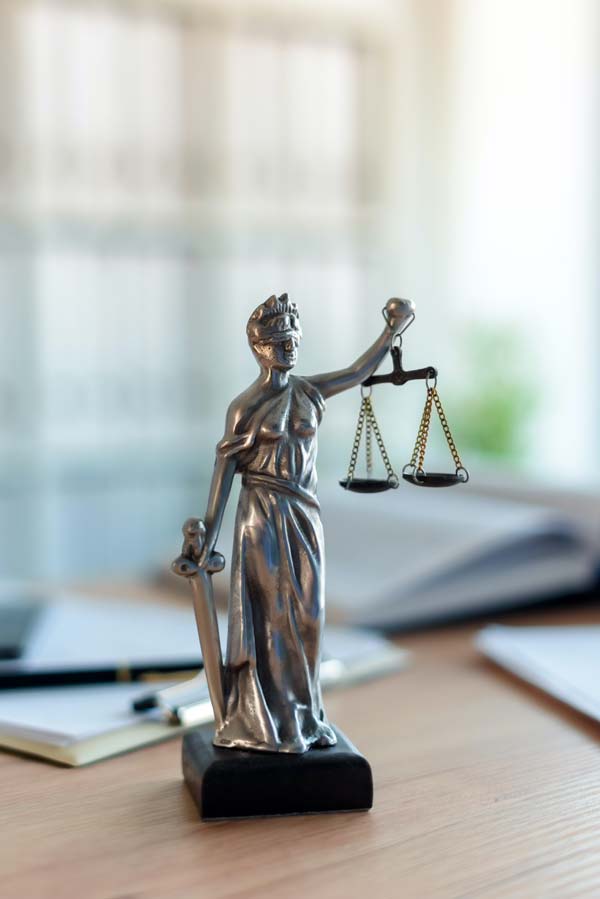 Statue der Lady Justice auf Schreibtisch in Anwaltskanzlei